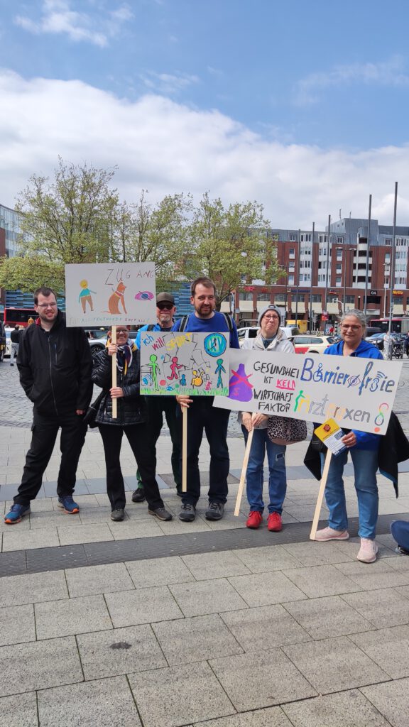 Eine Gruppenbild von Protestierenden, die Demoschilder in der Hand halten.